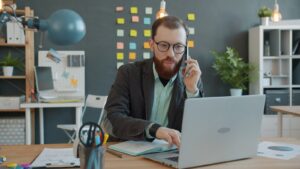 Man on phone working on laptop in office